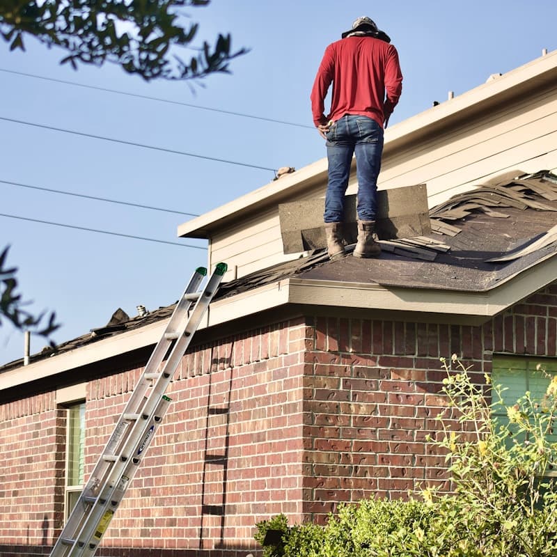 Roofing contractor inspecting a shingle tear-off on a residential roof